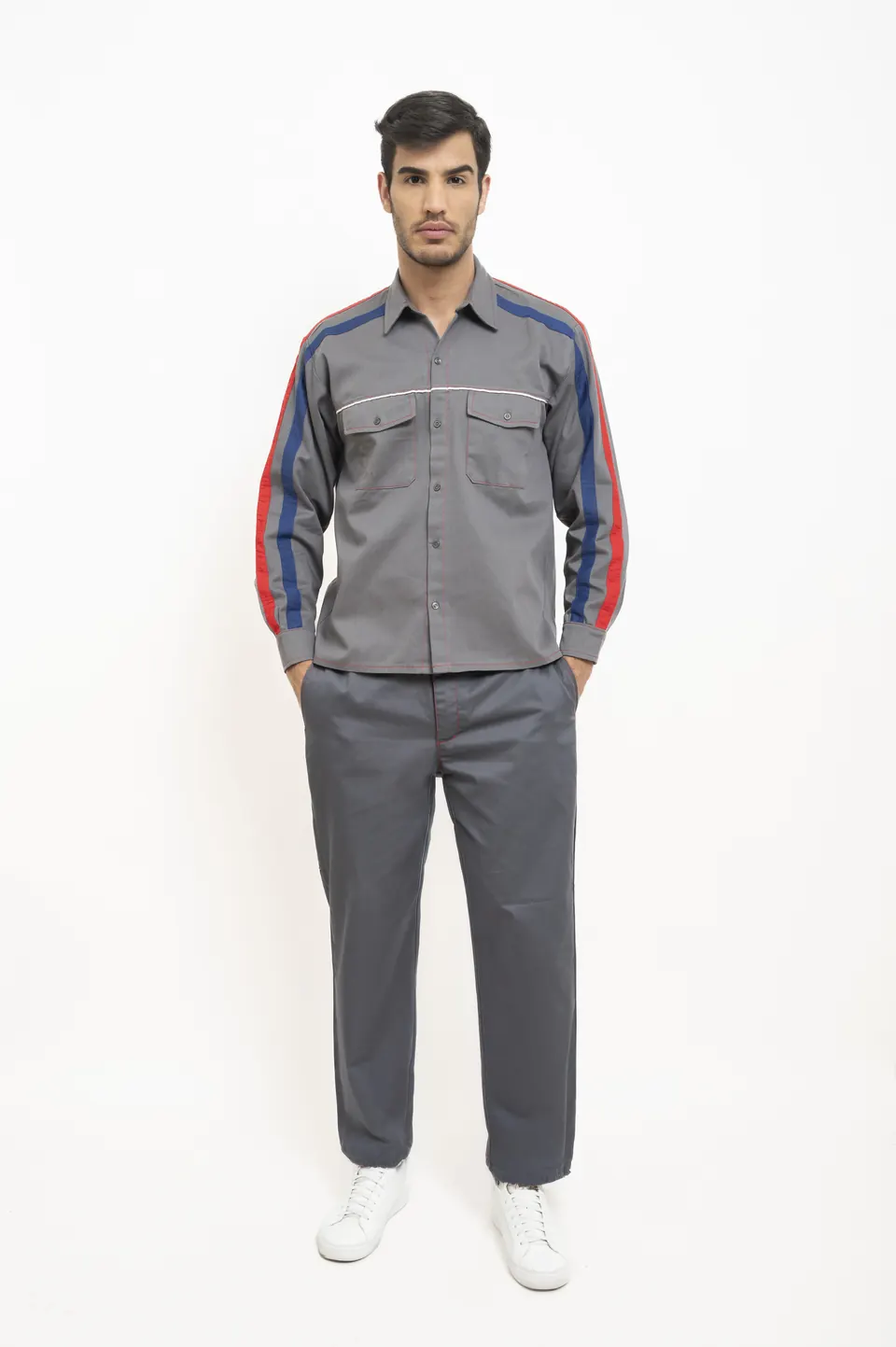 Hombre con camisa y pantalón grises de trabajo, con franjas roja y azul en las mangas