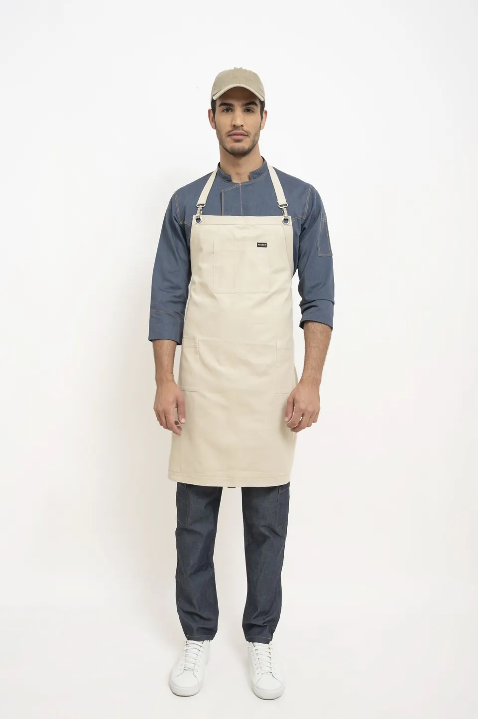Hombre con delantal beige y gorra sobre camisa de jean